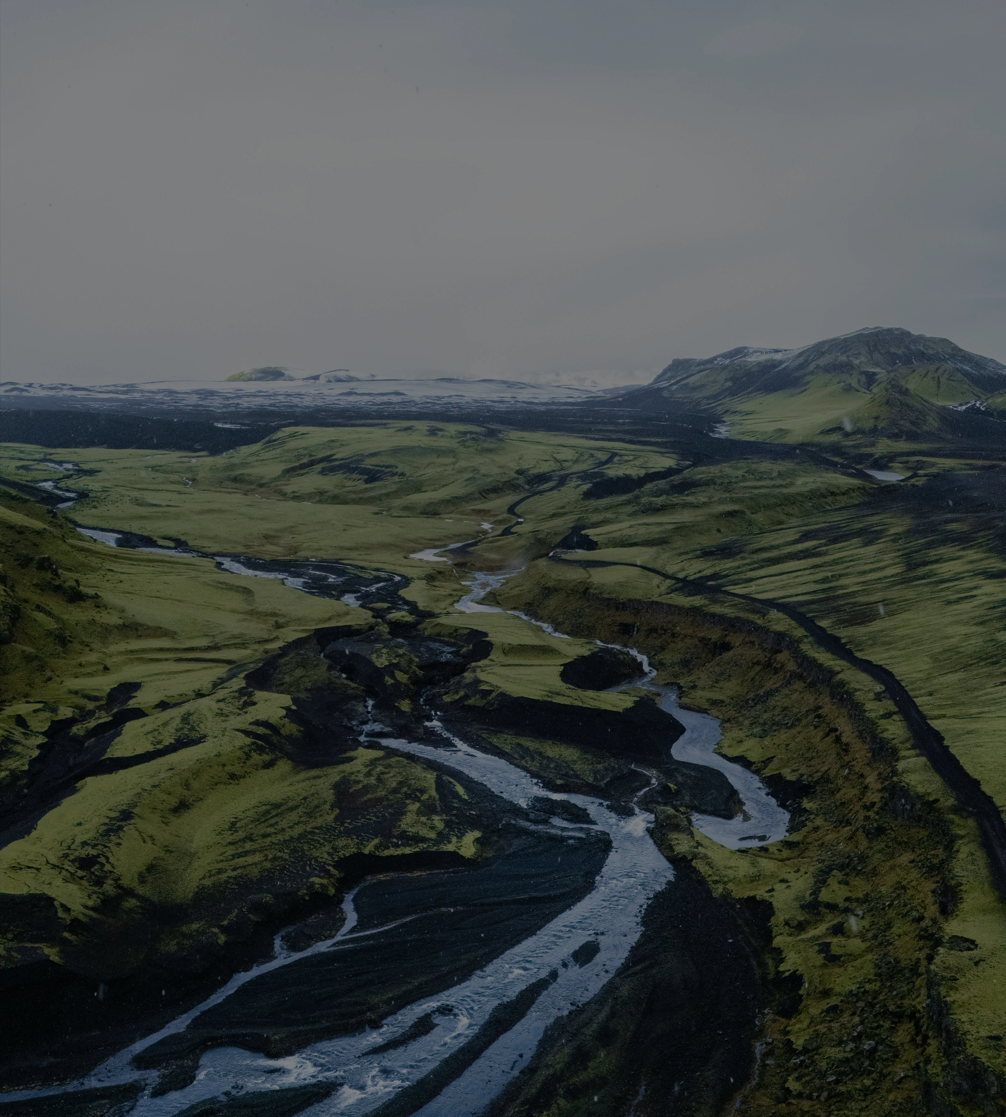 A glacial river braiding across a green valley, seen from the air